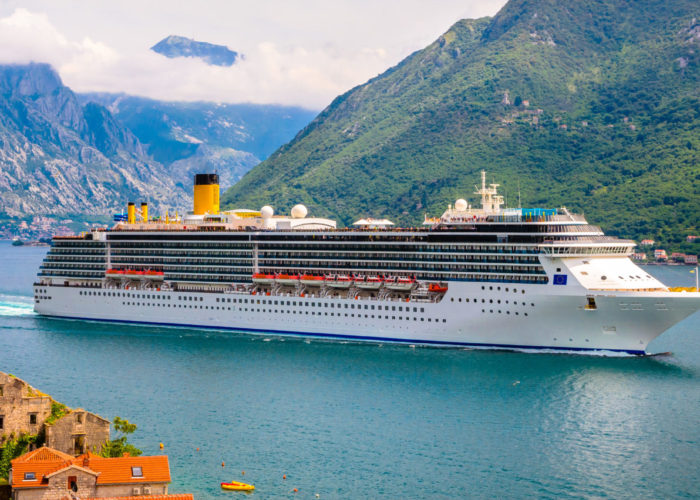 Cruise ship in water in front of lush green mountains