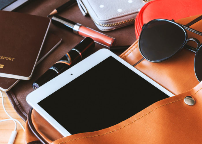 Aerial view of large carry-on bag spilling out travel gear and gadgets across the table