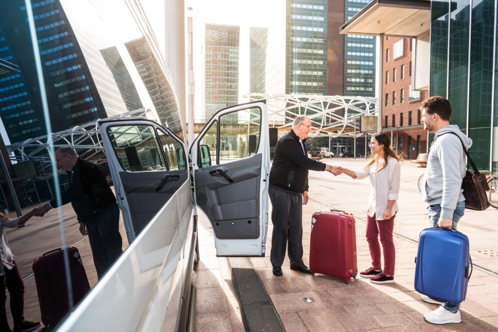 Two people greeting the driver of an airport to hotel shuttle