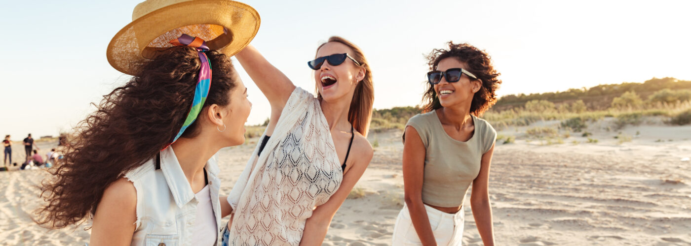 Three friends laughing and walking on the beach