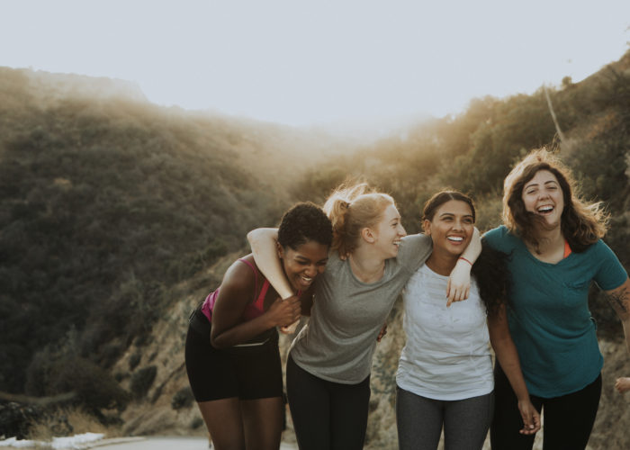 Four friends hiking up a mountain path in warm sunlight