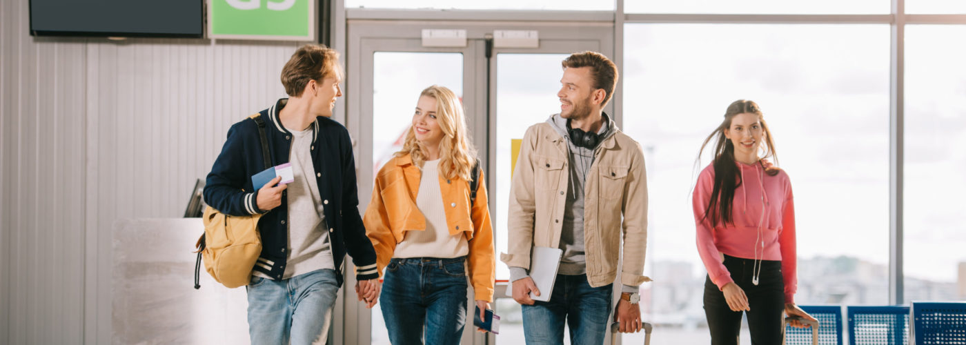 Four friends walking to an airport terminal