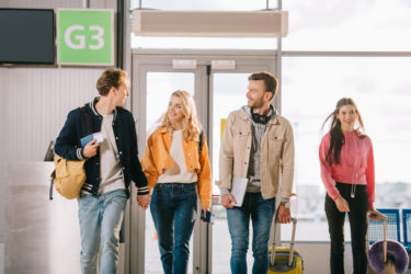 Four friends walking to an airport terminal