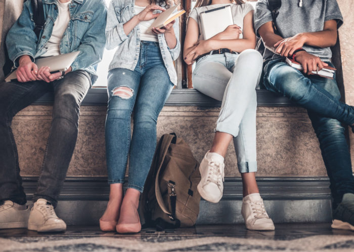 Four people wearing denim sitting on a bench