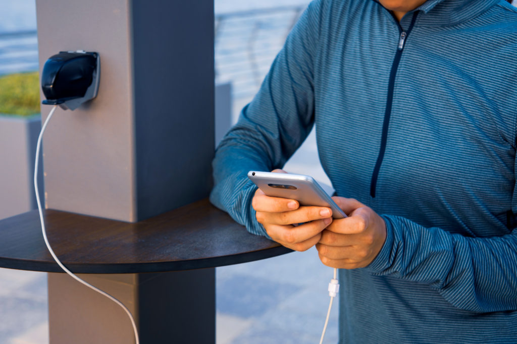 Person charging their cellphone at an airport charging station