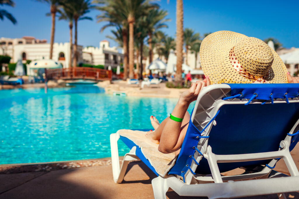 Woman relaxing by the pool on a clear day at an all-inclusive resort