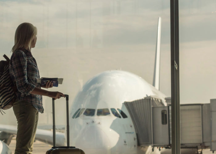 Woman with luggage standing in dark terminal in front of window