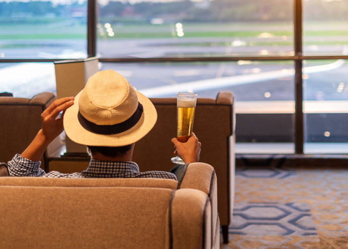 Man holding a full glass of beer in an airport terminal