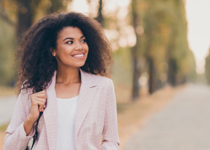 Woman walking on an autumn road wearing a pink blazer