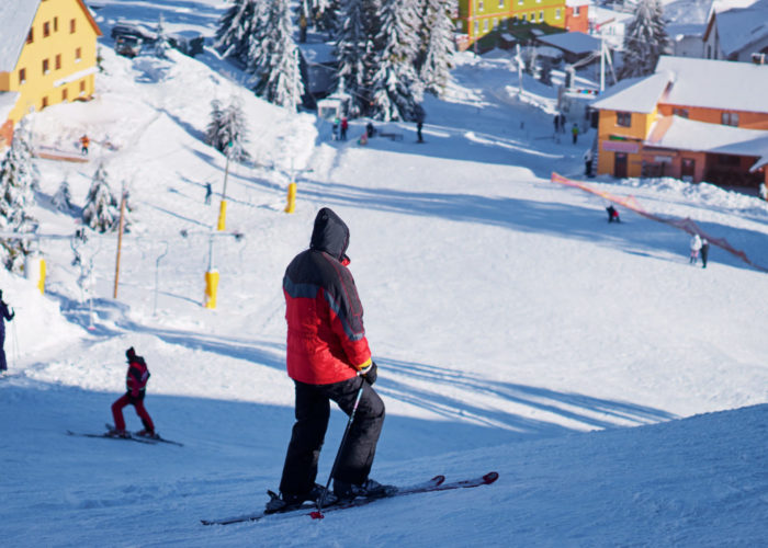 People skiing downhill toward a village in the snow