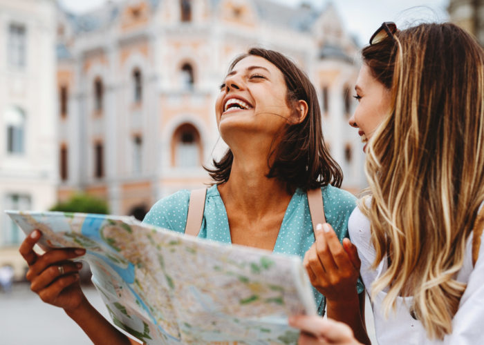 Two women laughing a reading a map in a European city