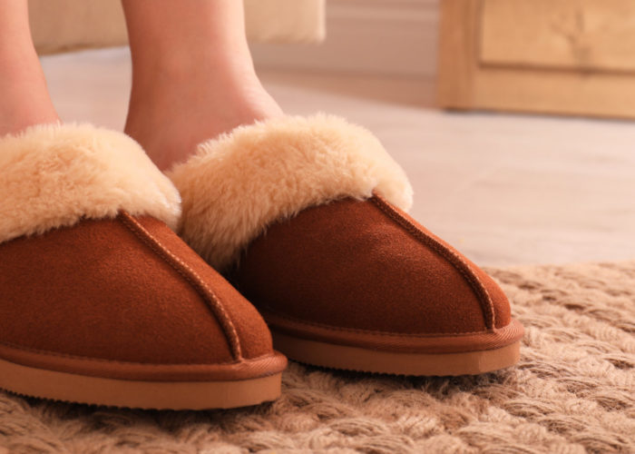 Close-up of person's feet in slippers in house