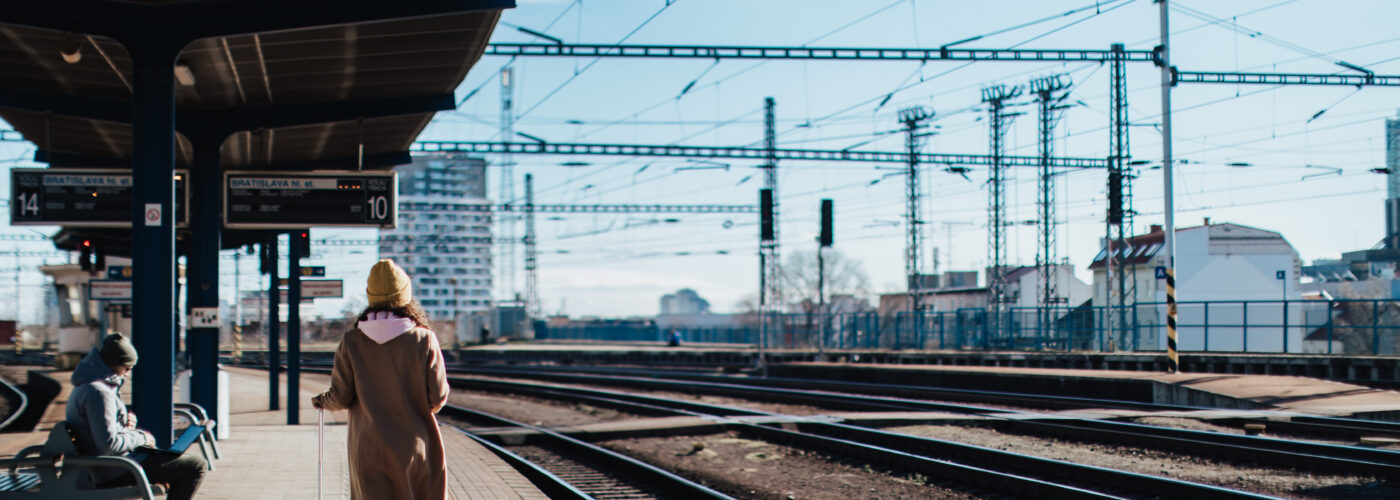 Single person waiting for train with luggage at an outdoor station