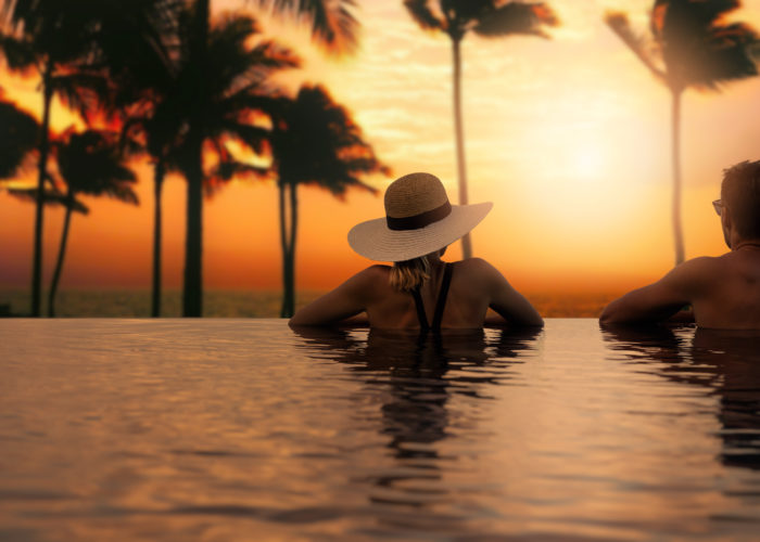 Couple looking over edge of infinity pool at sunset