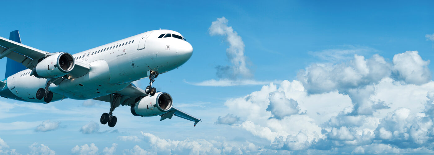 Airplane mid-flight in a blue sky with white clouds