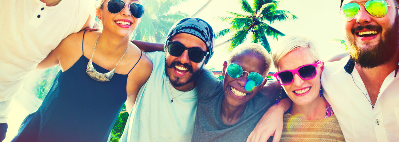 Friends on beach smiling and wearing sunglasses