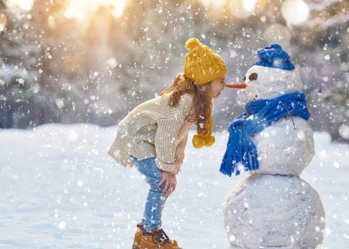 girl playing with snowman on a snowy winter walk