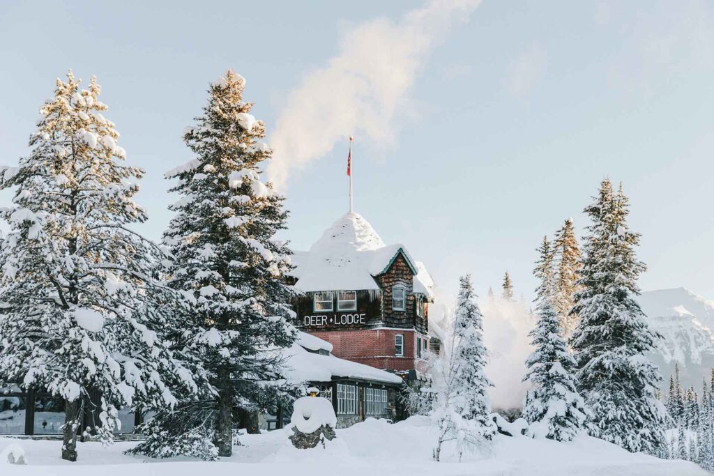 Exterior of the Deer Lodge covered in snow and surrounded by trees