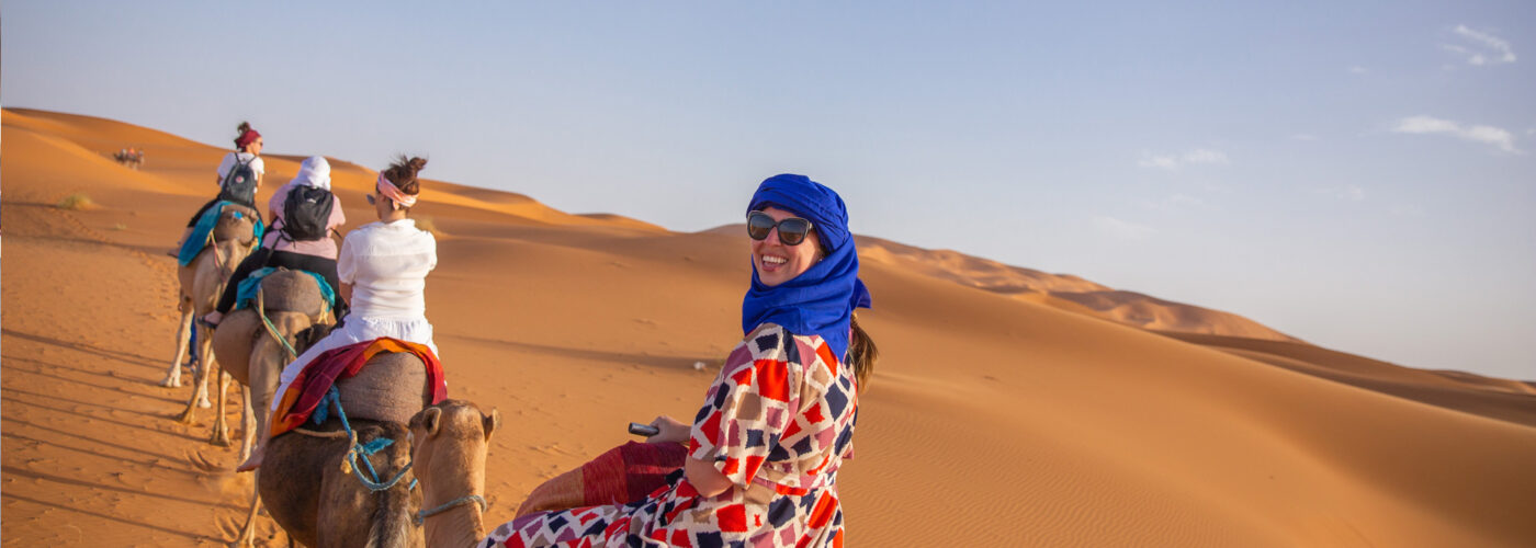 travelers ride on camels in shara desert Staff FOC trip to Morocco Uncovered (XMKC)