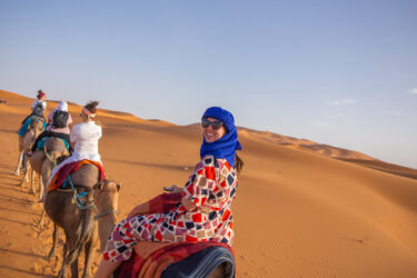 travelers ride on camels in shara desert Staff FOC trip to Morocco Uncovered (XMKC)