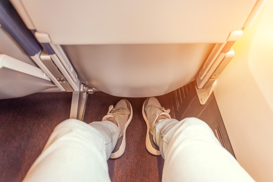 Enough legroom between the seats in the passenger plane, the view of the men's legs.