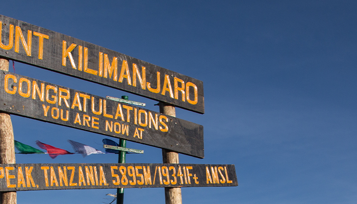 Sign at summit of Mount Kilimanjaro congratulating hikers for reaching the top